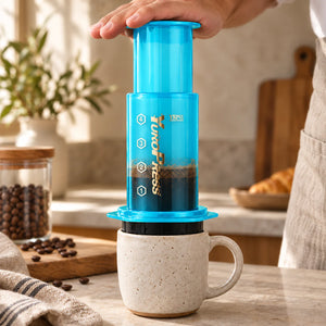 Mãos pressionam a Aeropress Cafeteira YuroPress Azul sobre uma caneca de cerâmica