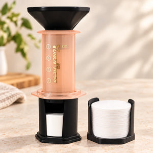 Aeropress Cafeteira YuroPress Laranja ao lado do porta-filtros e filtros de papel de 64 mm