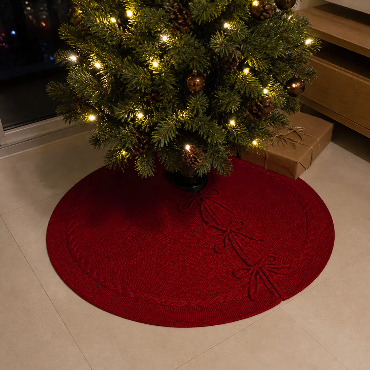Saia de Natal vermelha tricotada sob árvore iluminada em piso de porcelanato