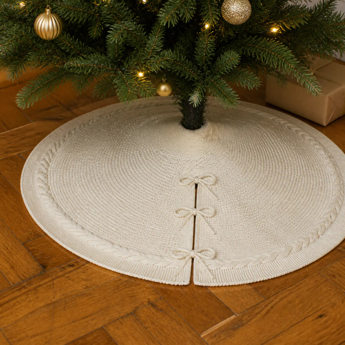 Detalhe da saia para árvore de Natal branca com três laços em piso de madeira