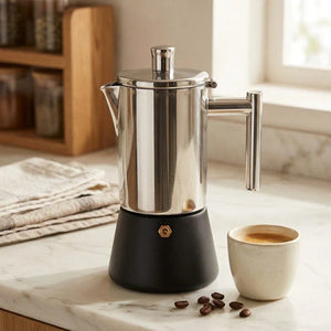 Cafeteira italiana inox Capri em bancada clara com xicara de cafe