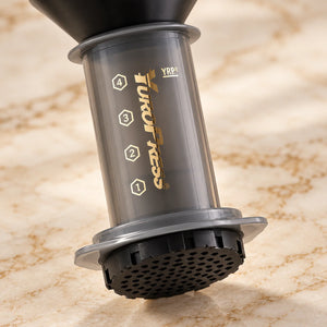 Detalhe da câmara cinza translúcida e da tampa perfurada da Aeropress Cafeteira YuroPress Cinza