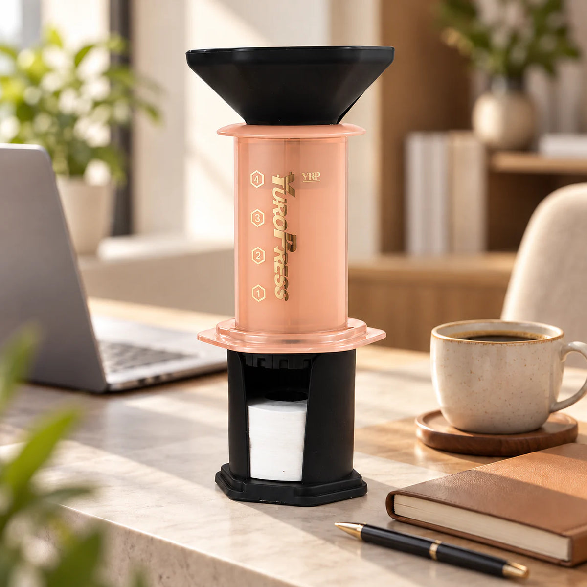 Aeropress Cafeteira YuroPress Laranja ao lado de notebook, caderno e caneca de café