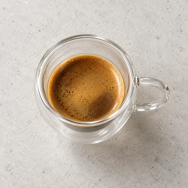 Vista superior de xícara de vidro de parede dupla com alça e espresso