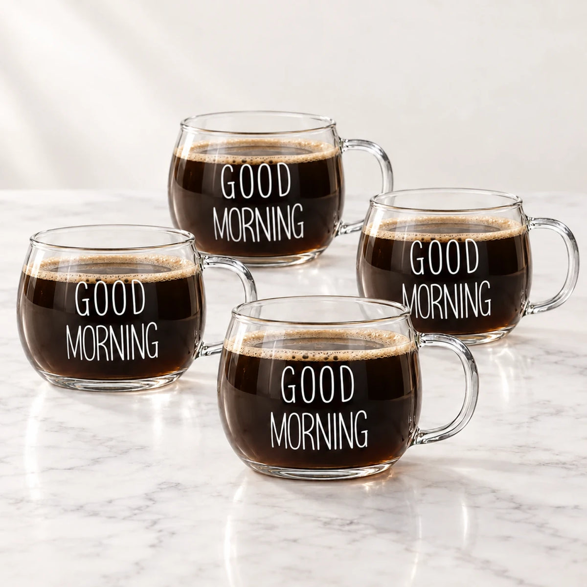 Quatro xícaras de vidro Good Morning Lumi Homi com estampa branca e café, sobre uma bancada clara