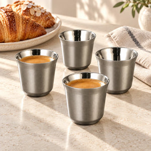 Quatro xícaras de café inox cinza Lumi Homi em uma mesa de café da manhã, duas com café