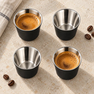 Vista superior de quatro xícaras de café inox pretas Lumi Homi, mostrando duas vazias e duas com café